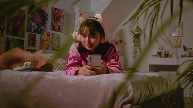 Teen Girl In Headphones Talks By Video Chat Using Phone - Stock 