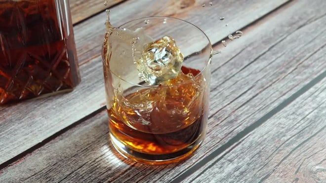 Premium Photo  Glass with whiskey and falling ice cube with splashes