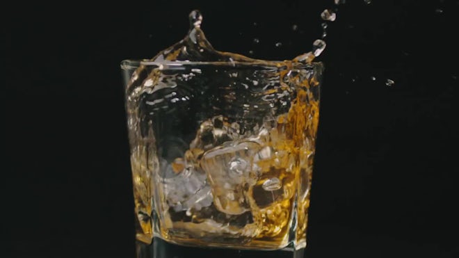 Premium Photo  Glass with whiskey and falling ice cube with splashes