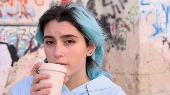 Blue haired Teenage girl in blue hoodie staying near graffiti wall with red water  bottle Stock Photo by katrinshine