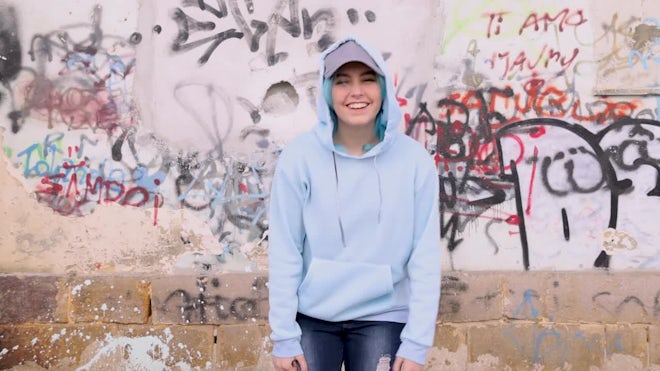 Blue haired Teenage girl in blue hoodie staying near graffiti wall with red water  bottle Stock Photo by katrinshine