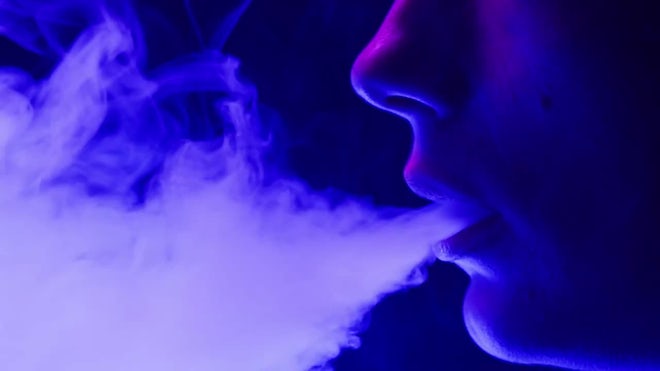 Young Woman Smoking Hookah Or Cigarette In Blue Neon Light