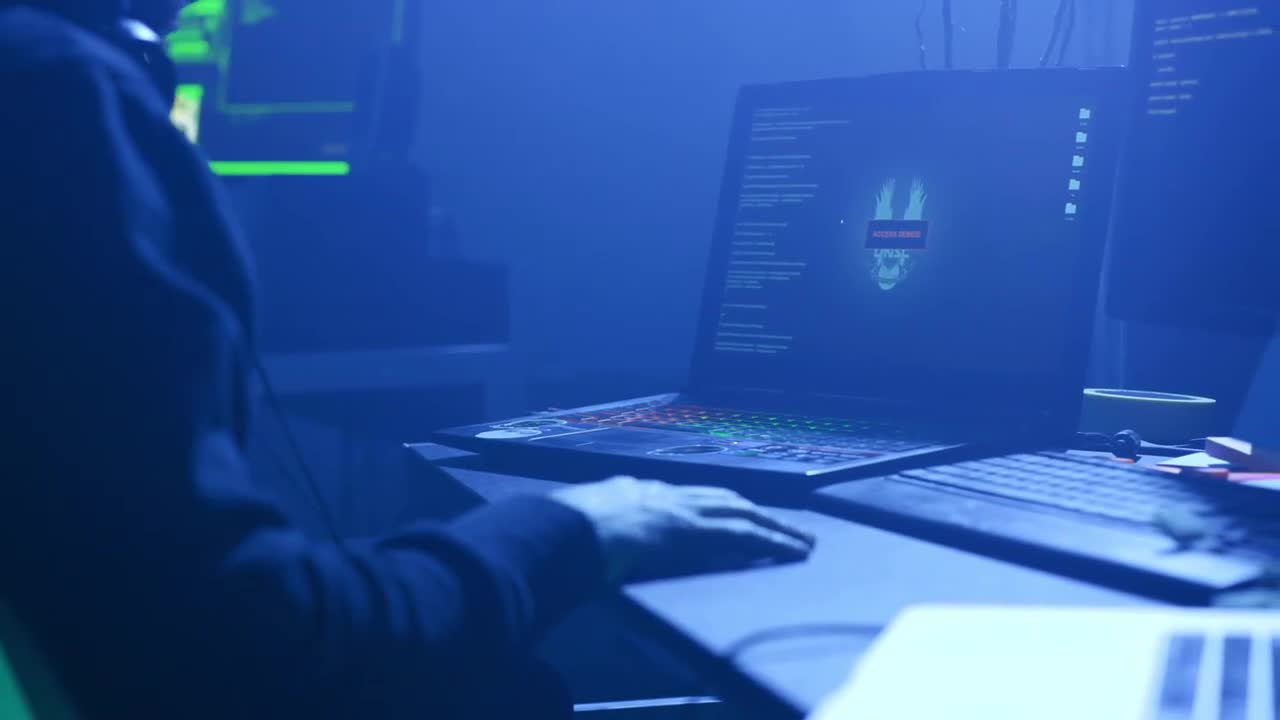 A Stealthy Hacker In A Dimly Lit Room Surrounded By Multiple
