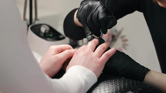 Nail Technician In Gloves Works On Client's Nails In A Salon