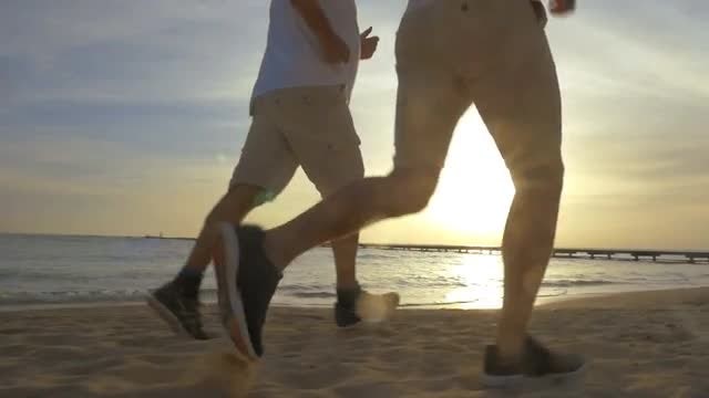 Two Men Jog On Beach: Stock Video