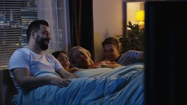 Family In Bed Watching TV: Stock Video