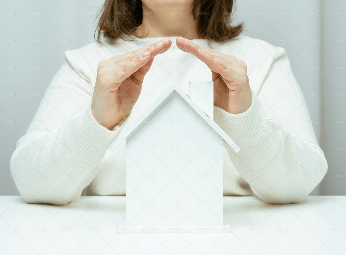 Hands Folded Above A Model House: Stock Photos