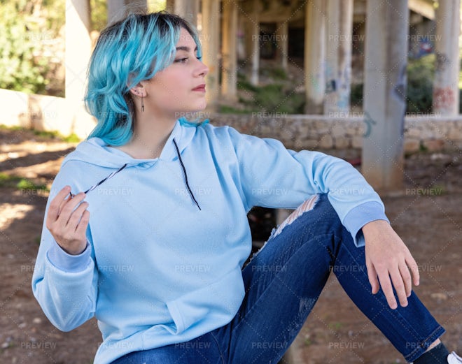 Blue haired Teenage girl in blue hoodie staying near graffiti wall with red water  bottle Stock Photo by katrinshine