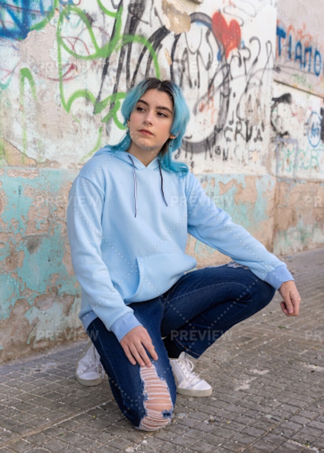 Blue haired Teenage girl in blue hoodie staying near graffiti wall with red water  bottle Stock Photo by katrinshine