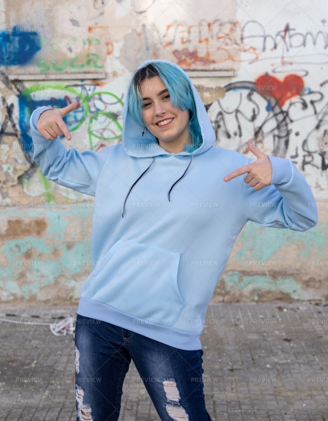 Blue haired Teenage girl in blue hoodie staying near graffiti wall with red water  bottle Stock Photo by katrinshine