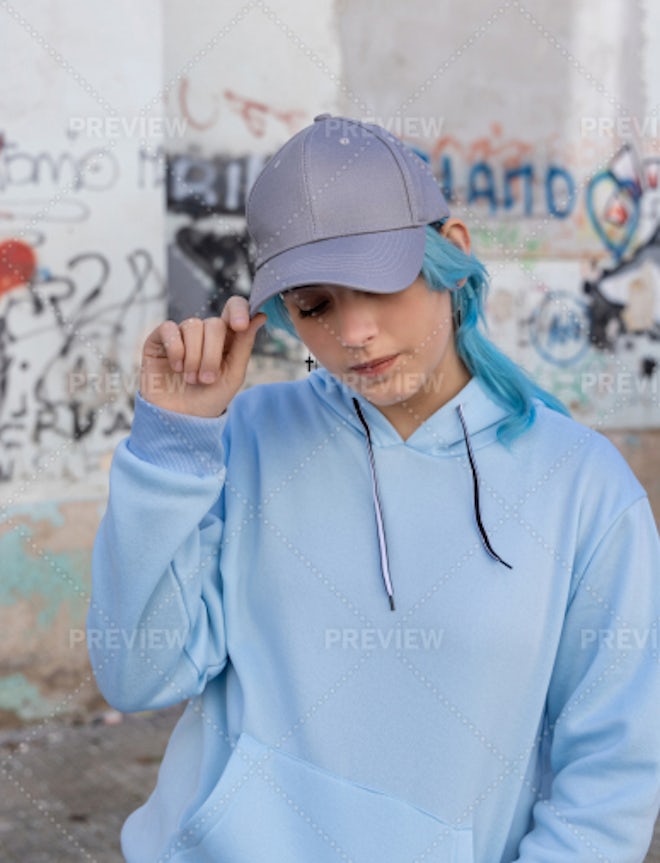 Blue haired Teenage girl in blue hoodie staying near graffiti wall with red water  bottle Stock Photo by katrinshine