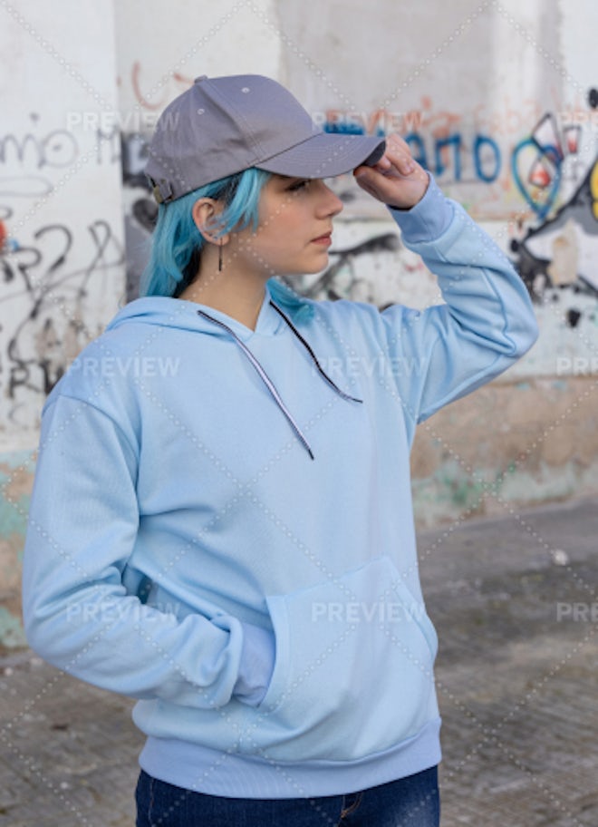 Blue haired Teenage girl in blue hoodie staying near graffiti wall with red water  bottle Stock Photo by katrinshine