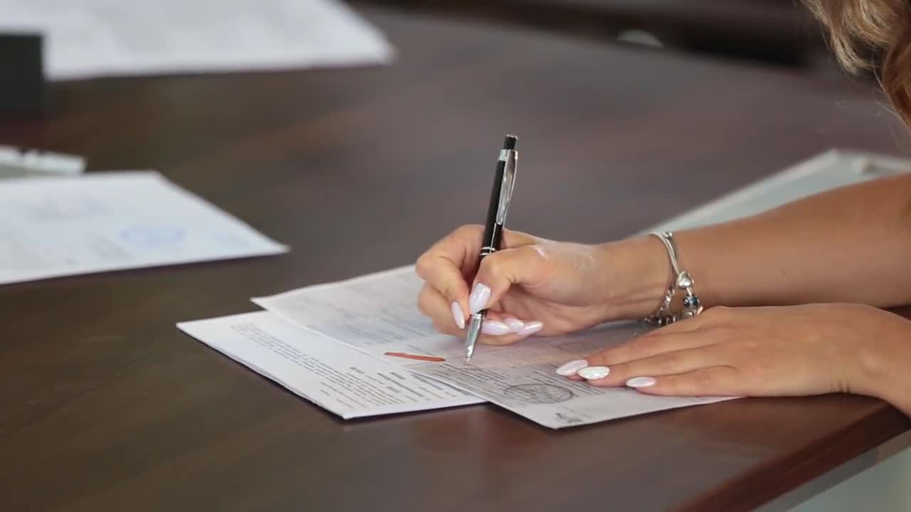  A person is signing an insurance policy document with a pen.
