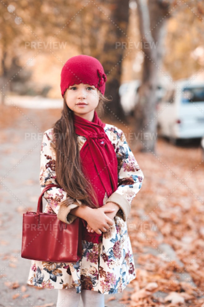 Pretty kid girl 4-5 year old wearing stylish autumn clothes in park.  Looking at camera. Fall season. Childhood. Stock Photo