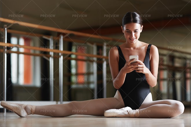 Ballerina in ballet pointe shoes stretches on barre. Woman practicing in  studio Stock Photo by Stock_Holm