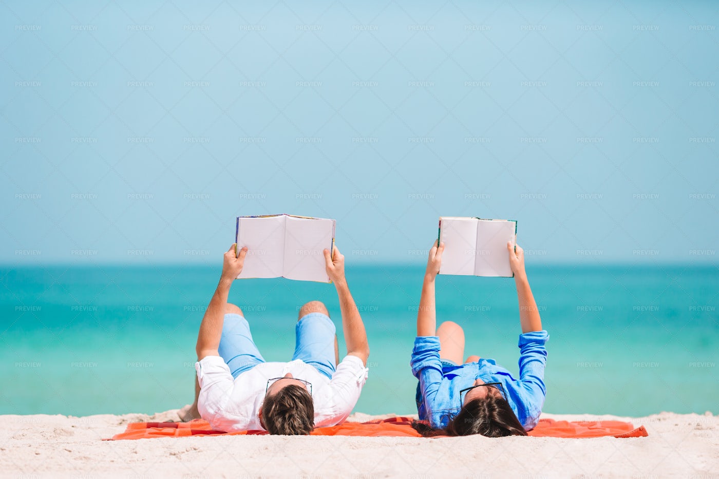Couple Reading On The Beach: Stock Photos