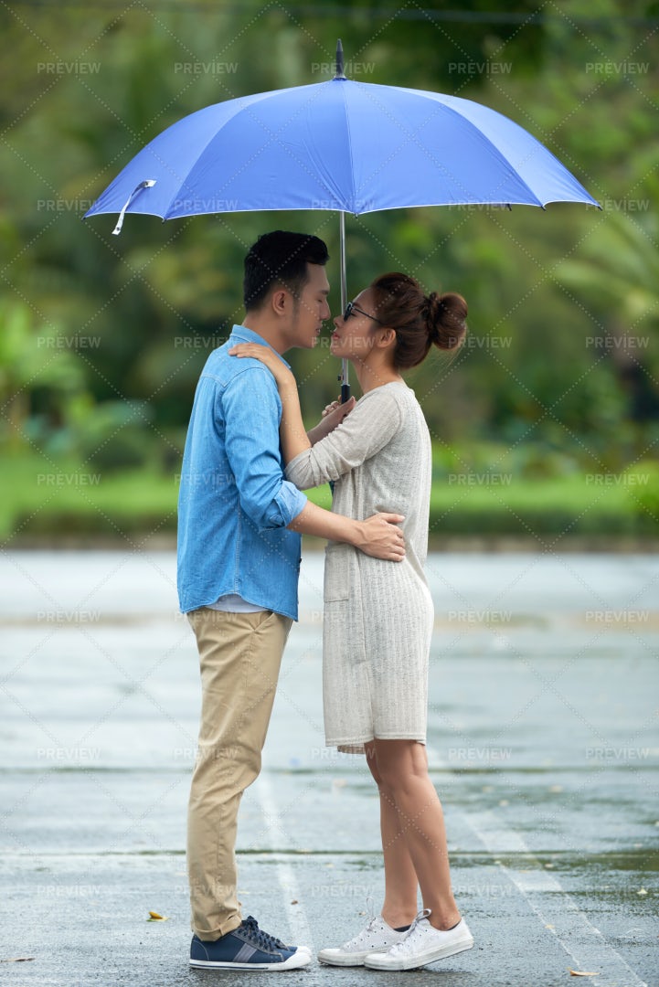 Asian Couple Kissing In The Rain: Stock Photos