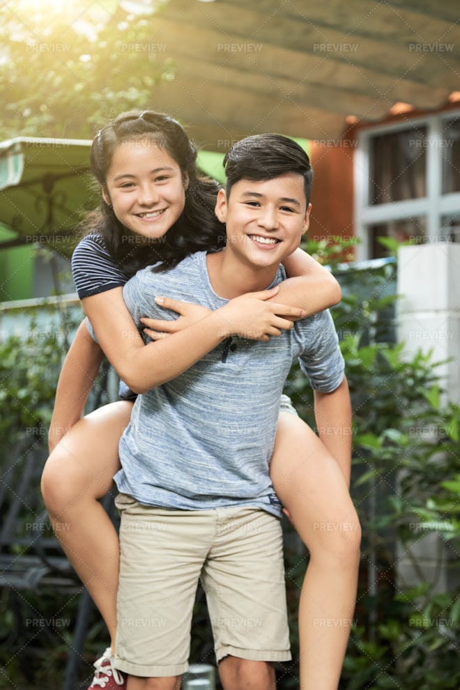 Young girl carrying sister giving piggyback ride Stock Photo