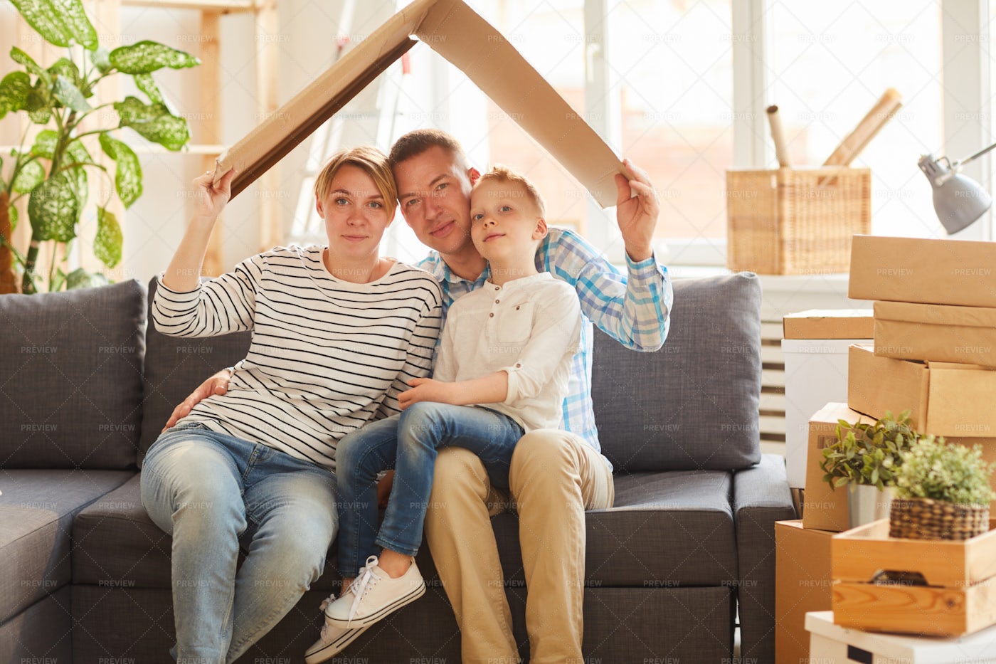 Family Holding Cardboard Roof Above...: Stock Photos