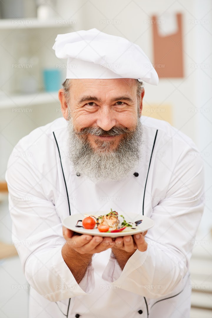Smiling Senior Chef Presenting Dish: Stock Photos