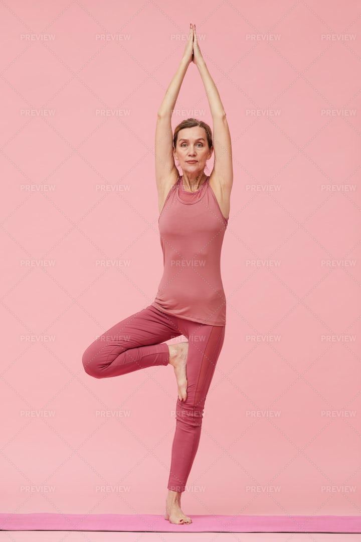 Mature Woman Enjoying Yoga On Pink: Stock Photos