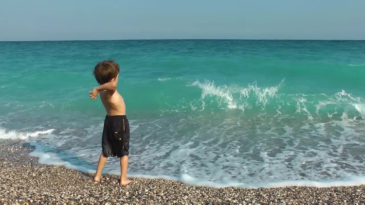 Boy Throwing Stones To The Sea: Stock Video