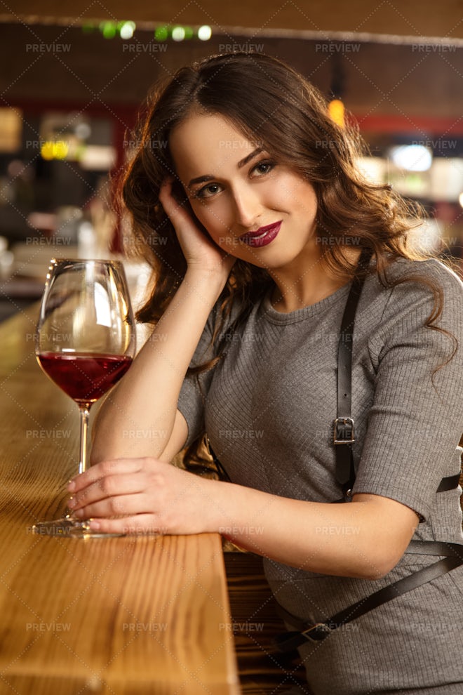 Businesswoman drinking from large wine glass with straw stock