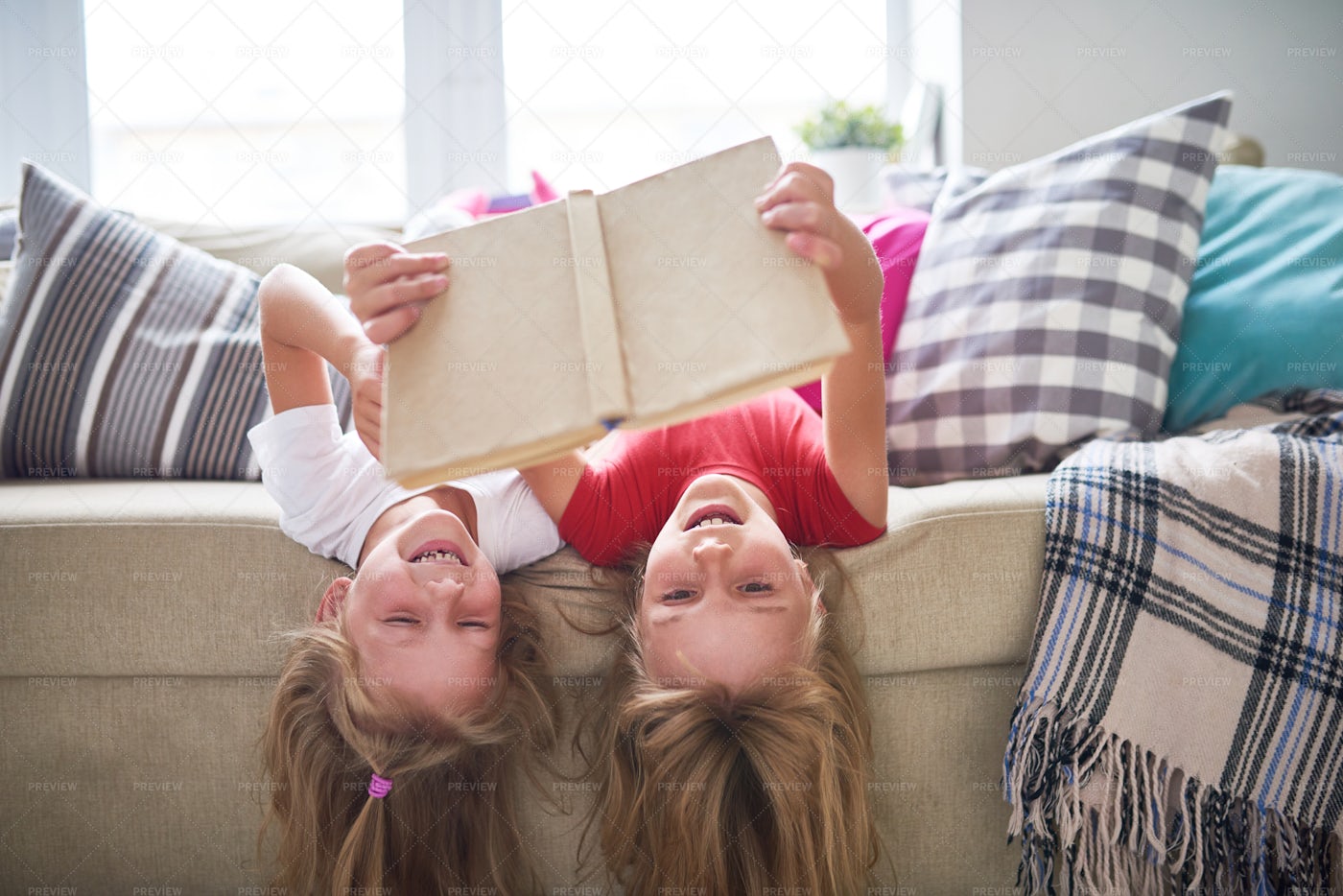 Sisters Reading Book Upside Down: Stock Photos