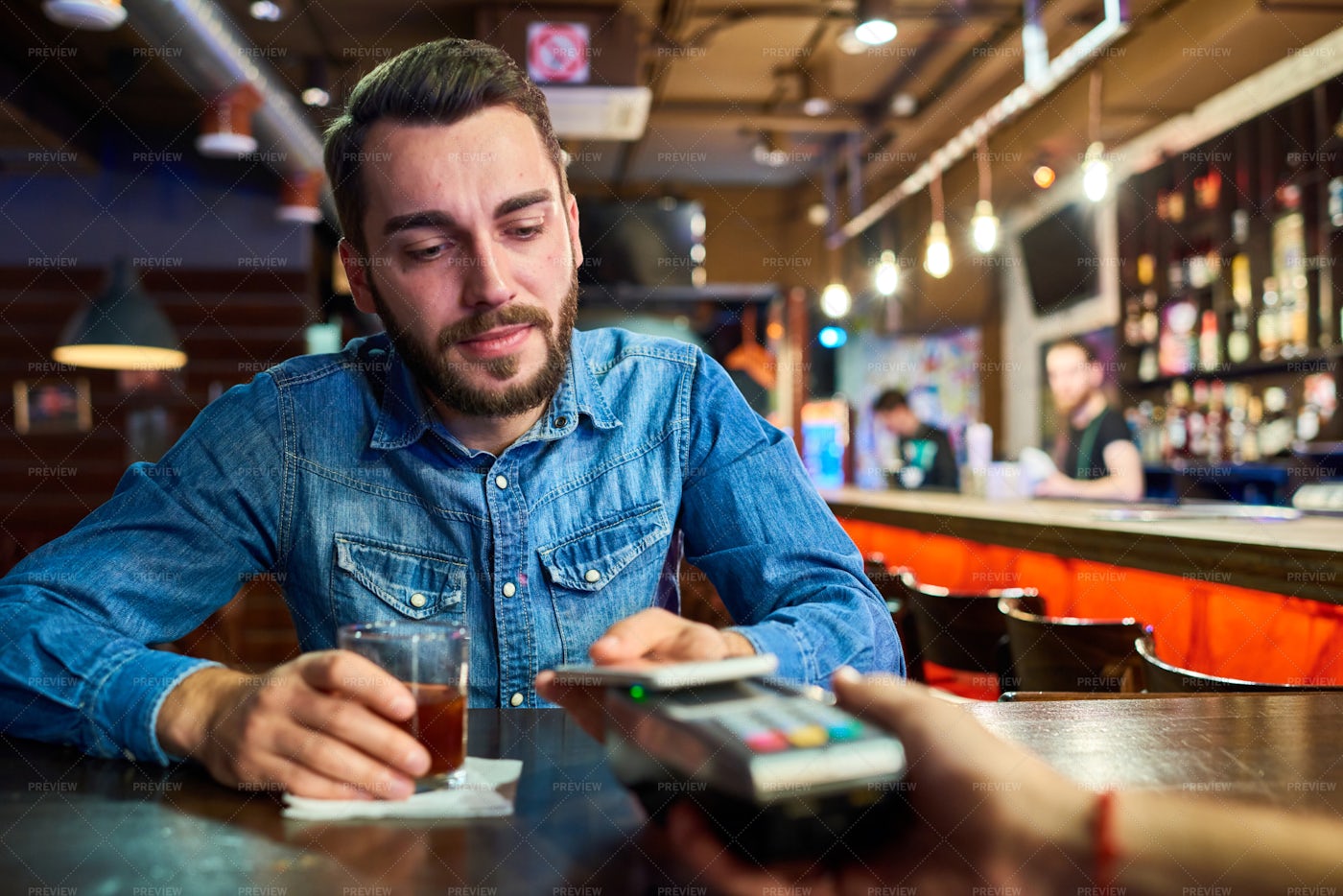Drunk Man Paying Via NFC In Pub: Stock Photos