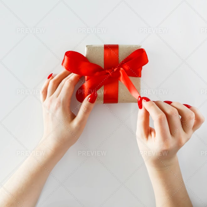 Female hand hold a box wrapped in red paper and tied with a red silk ribbon,  holiday Stock Photo by ndanko