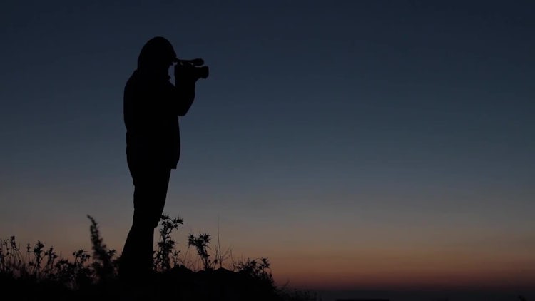 Silhouetted Man Holds Camera Outdoors: Stock Video