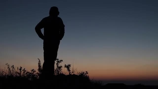 Silhouetted Man With Arms Akimbo: Stock Video