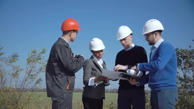 Four engineers standing in open field: Stock Video
