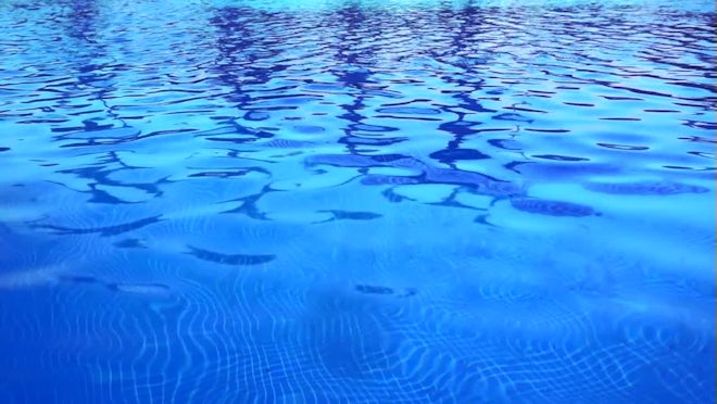 Light Blue swimming pool rippled water texture reflection. Beautiful blue  water background with glare from the sun. Stock Photo