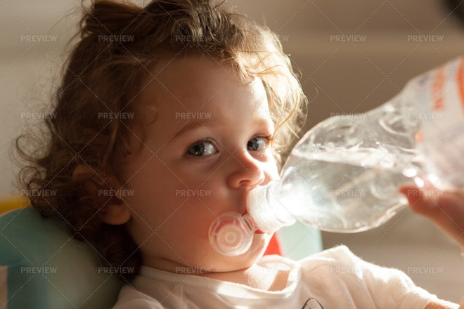 Toddler girl drinking water from the baby bottle Stock Photo