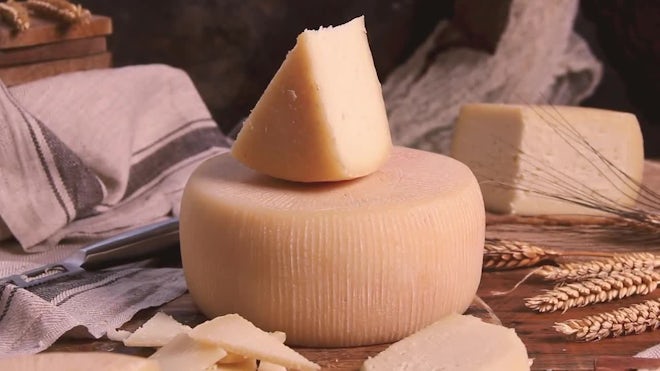 Closeup of a man slicing a Parmigiano Reggiano cheese wheel Stock