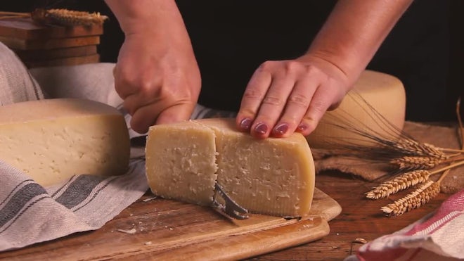 Closeup of a man slicing a Parmigiano Reggiano cheese wheel Stock