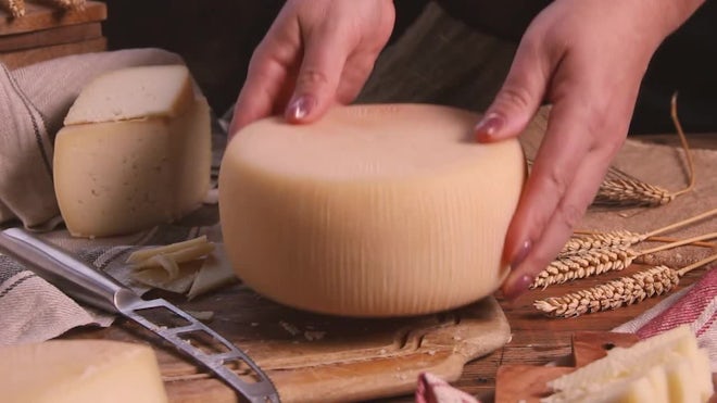 Closeup of a man slicing a Parmigiano Reggiano cheese wheel Stock